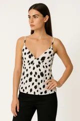 Musculosa blanca con estampado de manchas negras, breteles finos, escote en V y cierre lateral.