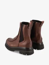 Bota de caña media confeccionada en cuero negro, con cierre frontal metálico y paneles elásticos laterales. Presenta una suela robusta tipo track con base dentada y tirador en la parte posterior.