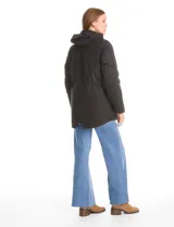 Campera 3 en 1 de color beige, con sistema de capas desmontables. La capa exterior es de tejido técnico resistente al viento y lluvia ligera, con capucha fija, cierre frontal con solapa, bolsillos de parche y ajuste elástico interno en la cintura. Incluye una campera interior capitoneada ultraliviana que puede usarse de forma independiente.