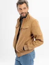 Campera de estilo casual confeccionada en tejido suave con textura tipo gamuza. Presenta cuello alto, cierre frontal, bolsillos laterales y bolsillos frontales con solapa. Incluye detalles de costuras en las mangas y terminaciones elastizadas en puños y cintura.