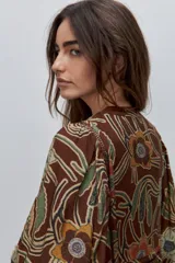 Vestido largo de silueta amplia y caída fluida, con estampado y recortes fruncidos que aportan movimiento. Presenta escote con abertura, cierre frontal con botones y mangas largas de volumen amplio con puños elastizados.