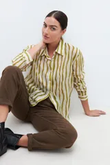 Camisa de manga larga con estampado a rayas verticales en tonos pistacho y blanco, con cuello clásico y cierre frontal con botones.