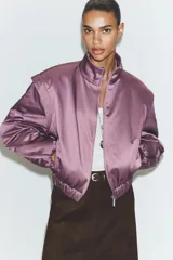 Chaqueta acolchada de cuello subido con cierre frontal de cremallera, manga larga con hombros marcados y puños elásticos. Presenta un diseño con bajo elástico y acabado satinado.
