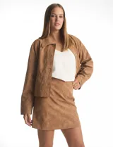 Minifalda de gamuza sintética color marrón con acabado aterciopelado, corte recto con costuras verticales decorativas y cierre lateral invisible.