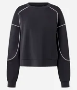 Buzo deportivo de corte oversized en color azul, con cuello redondo, manga larga y puños ajustados. Presenta detalles de frisos contrastantes en color blanco que recorren las mangas y el cuerpo de la prenda.