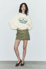 Sudadera de cuello redondo y manga larga, color bordó, con estampado frontal en blanco que dice "Chasing The Sunset's Glow SAN DIEGO 1980 PACIFIC HARBOR".