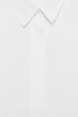 Camisa de manga corta y corte fluido, color marrón, con cuello solapa y cierre frontal con botones ocultos. Presenta bajo asimétrico con aberturas laterales y mangas con vuelta.