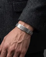 Pulsera de acero inoxidable con placa central rectangular que presenta un diseño de patrón de tablero de ajedrez grabado y cadena de eslabones tipo bizantina.