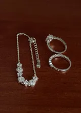 Conjunto de joyería de tres piezas en plata 925 y zirconias, compuesto por una pulsera con cadena y zirconias colgantes, un anillo medio sin fin con zirconias y un anillo solitario con zirconias en corte gota y pavé lateral.