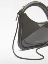 Bolso de cóctel Adolfo Domínguez de estructura rígida y acabado brillante. Presenta un diseño asimétrico con asa tubular integrada y correa larga extraíble. Cuenta con cierre magnético y logo de la marca estampado en dorado.