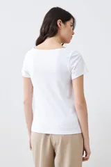 Remera de manga corta con escote bote, confeccionada en tejido liso de color blanco, con un corte ajustado y versátil.