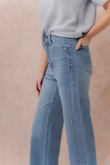 Jean de denim celeste con lavado claro, corte recto y tiro medio-alto, con diseño de cinco bolsillos y cierre frontal con botón y cremallera.