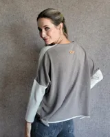 Sweater de corte holgado y diseño bicolor, con frente en color crema y espalda y mangas en color gris. Presenta cuello redondo y terminaciones en tejido acanalado.