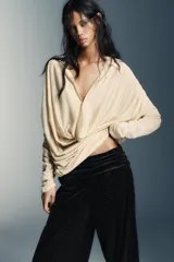 Pantalón negro de tiro bajo, confeccionado en terciopelo con pequeños puntos brillantes. Presenta cintura elástica con pliegues, caída ancha tipo baggy y puños ajustados en los tobillos.