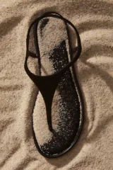 Sandalias planas de dedo color negro, con diseño minimalista y tira fina en el empeine con sujeción trasera elástica.
