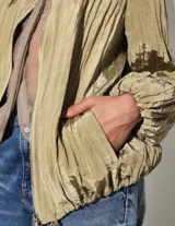 Campera liviana de acabado satinado con textura plisada, cuello alto, cierre frontal, bolsillos laterales, puños elastizados y cordón regulable en la cintura.
