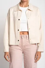 Camisa tipo sobrecamisa oversize color crudo, confeccionada en tejido de gamuza vegana con cierre frontal de botones metálicos y cuello clásico.