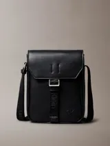 Morral Calvin Klein modelo Cargo Reporter, color negro, confeccionado en poliuretano con diseño estructurado, solapa frontal y cierre de hebilla. Cuenta con correa de hombro ajustable y detalles de la marca grabados.