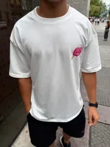 Remera blanca de corte oversize con cuello redondo y manga corta. Presenta un pequeño estampado en el pecho izquierdo que representa un helado de palito con el texto BHN.