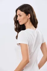 Remera blanca de manga corta y cuello redondo, con estampa frontal ilustrativa de un paisaje urbano con escalinatas en tonos azules y tierra.