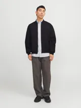 Campera bomber negra Jack & Jones de tejido plano liviano, con cuello baseball, cierre frontal de cremallera, bolsillos delanteros y puños de canalé. Confeccionada en poliéster y poliéster reciclado.