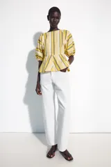 Camisa de algodón con rayas amarillas, blancas y grises, cuello redondo, mangas cortas abullonadas con puños elásticos y bajo con vuelo evasé.