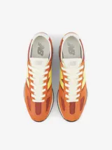 Championes urbanos New Balance modelo U471, con diseño inspirado en el running de los años 70. Presenta una combinación de colores naranja y bordó con el logo lateral en amarillo. Confeccionados con paneles de ante y material sintético, cuentan con entresuela de EVA y suela de goma con diseño de espiga.