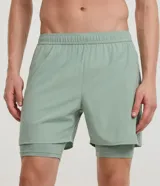 Bermuda deportiva verde militar con short de compresión incorporado, cintura elástica y cordón ajustable, confeccionada en microfibra de poliéster y elastano.