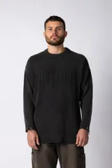 Sweater de punto grueso color negro con efecto gastado, cuello redondo, mangas largas y detalles de roturas en puños y ruedo. Presenta un diseño con letras bordadas al tono en el frente.