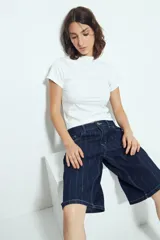 Bermuda de denim en color azul oscuro con diseño de rayas verticales blancas. Presenta un corte holgado, tiro medio y cierre frontal con botón y cremallera.