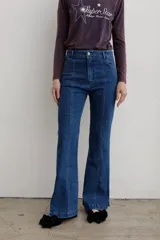 Jean de denim azul de tiro medio, con corte flare y costuras frontales destacadas.
