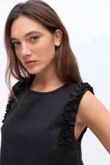 Musculosa negra con cuello redondo y detalles de volados en los hombros, confeccionada en una mezcla de algodón y Tencel.