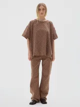 T-shirt oversize de denim con estampado de rombos en tonos azules, cuello redondo y mangas cortas. Presenta un bordado de estrellas blancas en el pecho y costuras visibles en color marrón claro.