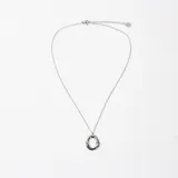 Collar de cadena fina de acero con dije circular de diseño orgánico e irregular.