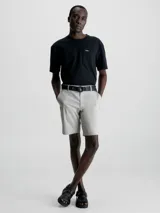 Shorts color crema de sarga de algodón orgánico con elasticidad añadida, talle medio, bragueta con cremallera, bolsillos laterales y traseros, cinturón con hebilla en forma de D incluido y micrologo de Calvin Klein.