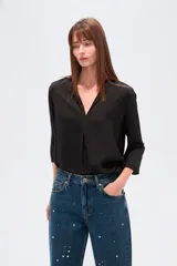 Blusa de poliéster color negro, con cuello en V, corte holgado y mangas tres cuartos.