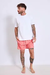 Short de baño de corte clásico en color celeste claro con estampado de pequeñas aves en tono oscuro. Cuenta con cintura elástica y un pequeño parche decorativo en el ruedo.