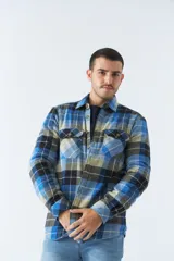 Sobrecamisa de algodón a cuadros color ladrillo, con interior de corderito, cierre con botones, bolsillos tipo cartera y logo en goma. El modelo usa talle M.