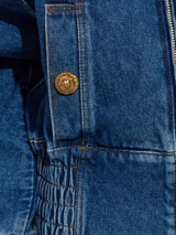 Campera de jean Balmain con cierre frontal, cuello alto y puños elásticos fruncidos. Presenta un diseño estructurado con hombros caídos y bolsillos laterales.