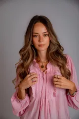 Camisa de color celeste con volados decorativos en el cuello y la parte delantera, cuenta con cordones para ajustar el escote, mangas largas con puños y corte holgado.