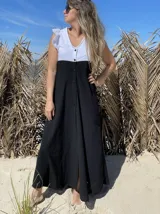 Vestido largo de corte evasé, con cuerpo superior blanco con volados en los hombros y falda negra con botones frontales.