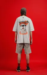 Remera de algodón premium color gris claro, corte oversize, con cuello redondo y manga corta. Presenta un estampado frontal pequeño con dos personajes de Disney (Mickey y Minnie) en llamas con el texto "THE FLAME OF LOVE".