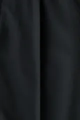Pantalón sastrero de sarga en color negro, con corte holgado, piernas amplias con raya marcada, cierre frontal con botón y corchete ocultos, bolsillos al bies y bolsillos traseros insertados.