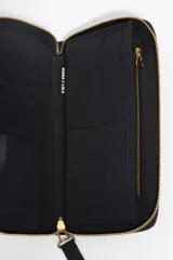 Billetera grande de nylon color negro con cierre perimetral de cremallera. Presenta un tirador de cordón bicolor con terminales metálicos y el logo de la marca estampado en dorado en el frente.