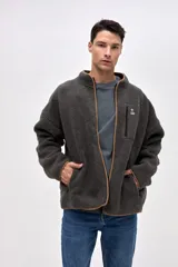 Campera de sherpa con diseño capitoneado en color crema. Presenta cierre frontal completo, cuello alto, bolsillos laterales y un bolsillo en el pecho con cierre en contraste. Incluye detalles en nylon y bordado decorativo en el pecho.