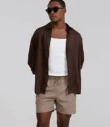 Bermuda de baño color beige, confeccionada en tejido ana ruga texturizado. Tiene lazo en la cintura, bolsillos laterales y un bolsillo trasero.