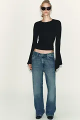 Camiseta de cuello redondo y manga larga, confeccionada en tejido rib con mezcla de lyocell. Presenta un diseño ajustado con terminación de volantes en los puños y bajo recto.