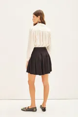 Short negro de tiro alto con pliegues y cinturón con hebilla metálica. El tejido presenta un sutil estampado jacquard.