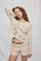 Sweater corto color crudo de manga larga, confeccionado en crochet calado con diseño artesanal y silueta amplia.