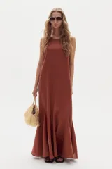 Vestido largo de lino marrón, sin mangas, con cuello a la base y canesú en la espalda. Cuenta con godets en el ruedo que le aportan movimiento y amplitud.